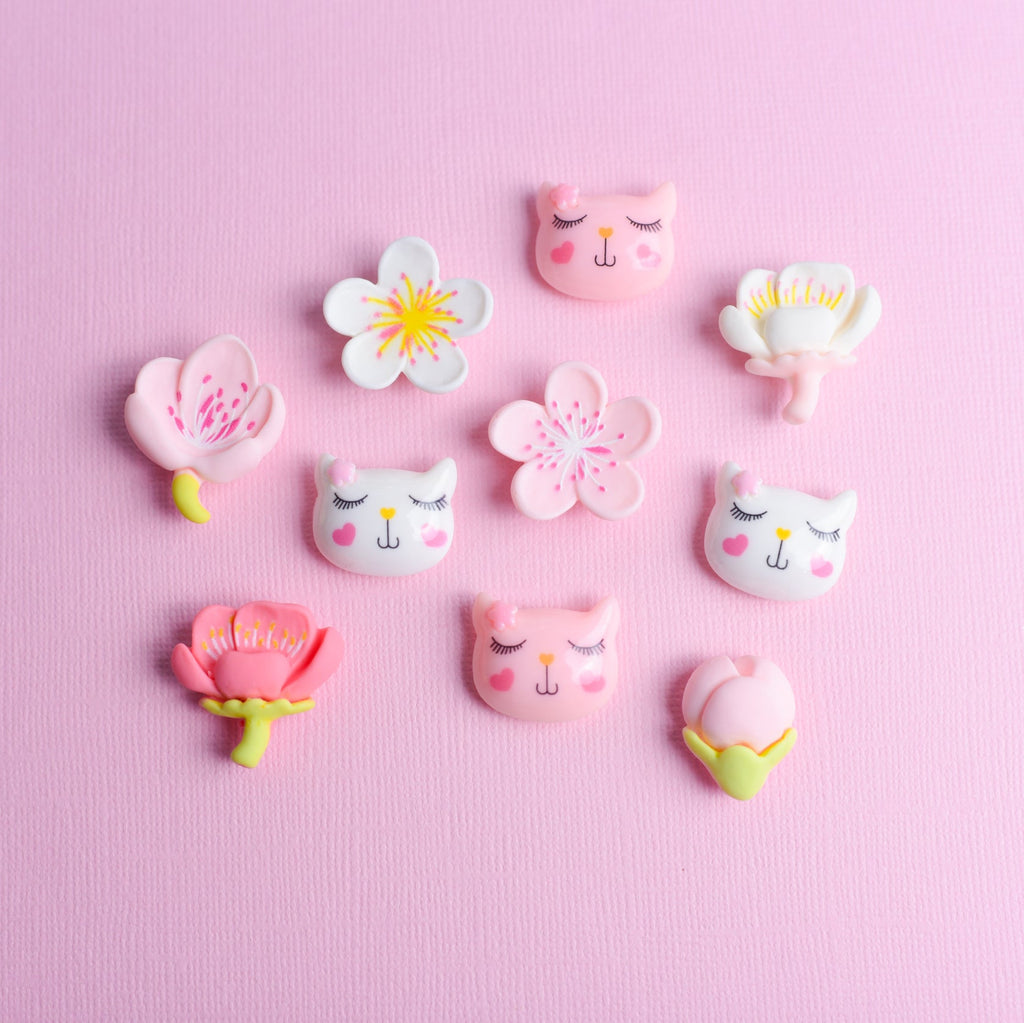 Decorative pins with cat and flower designs on a pink background