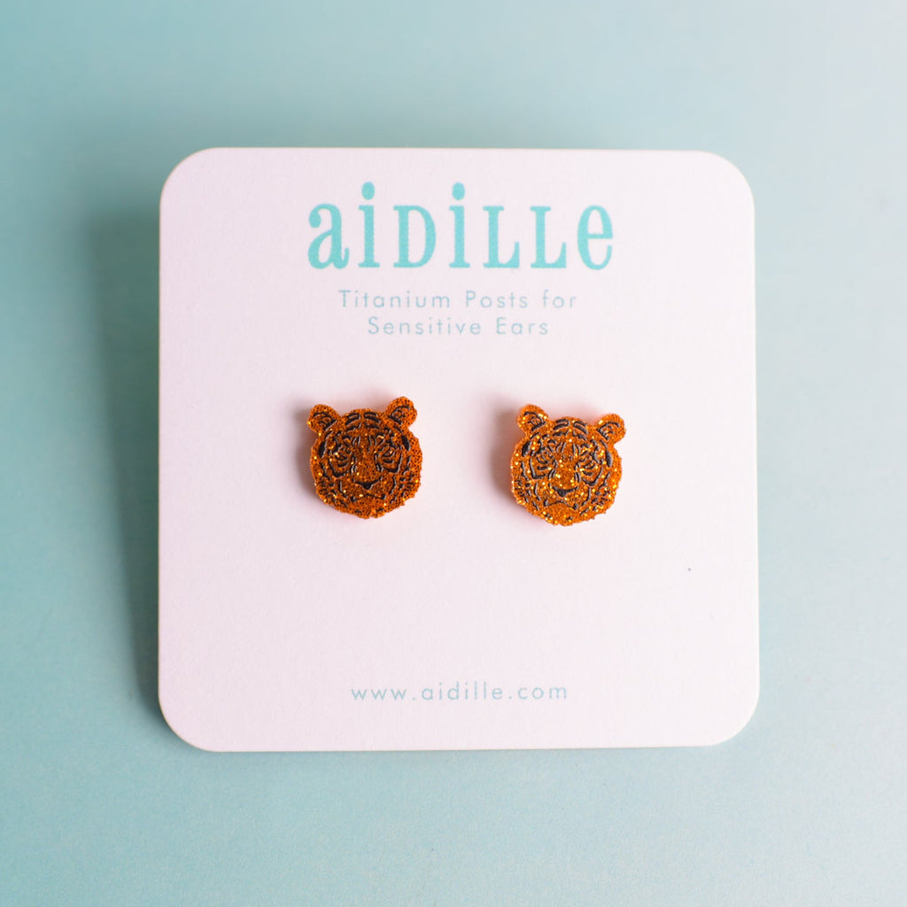 Tiger head earrings on a 'aidille' branded card against a light blue background