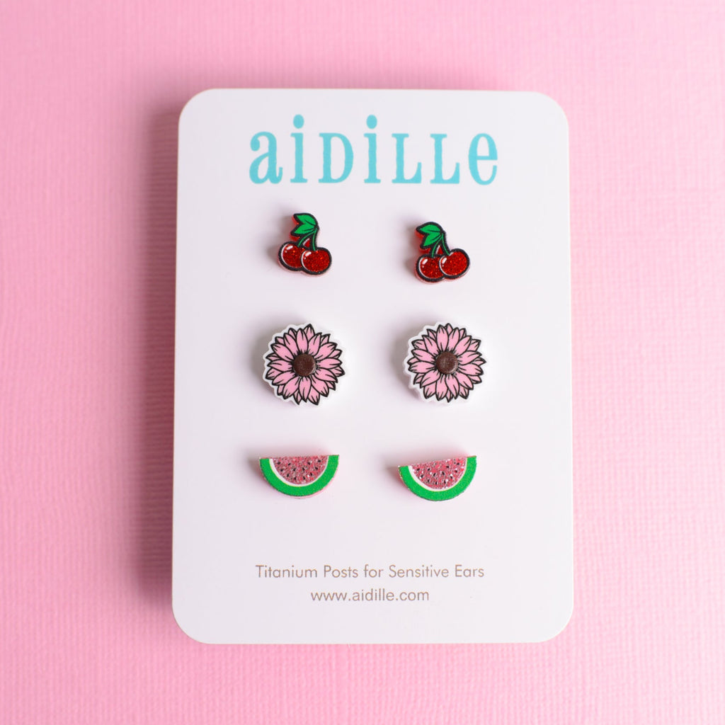 Set of earrings on a 'aidille' branded card against a pink background