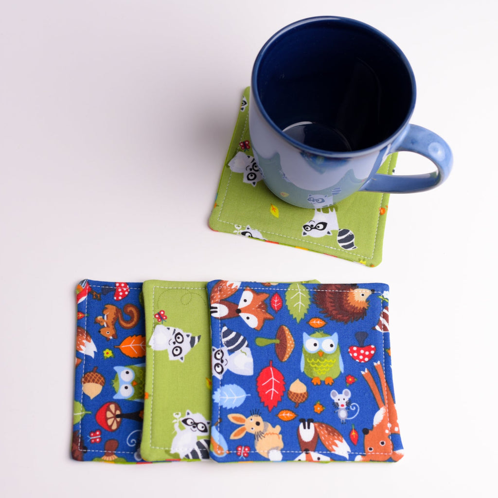 Set of colorful coasters with animal patterns and a blue mug on a white background