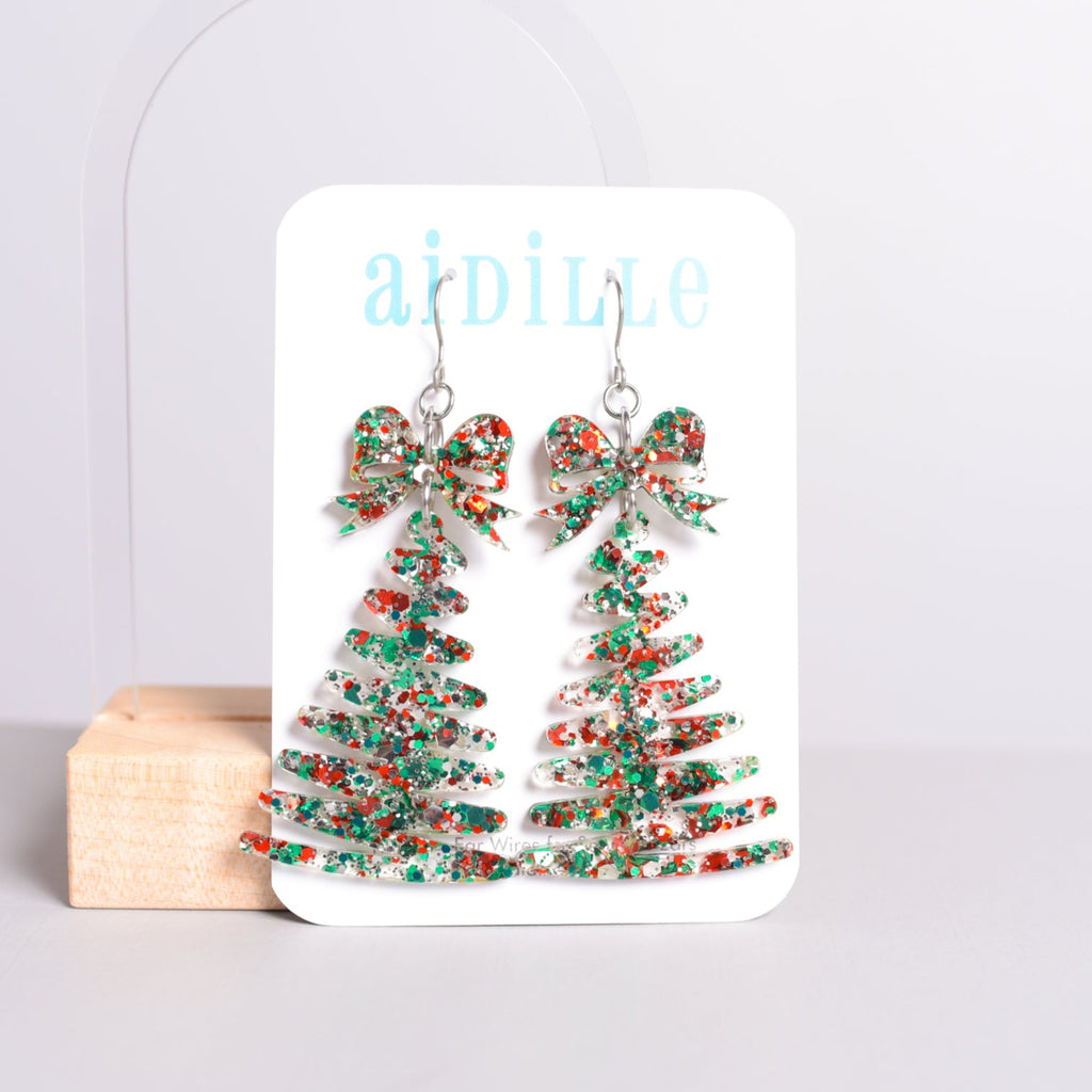 Christmas tree earrings on a branded card with a light gray background