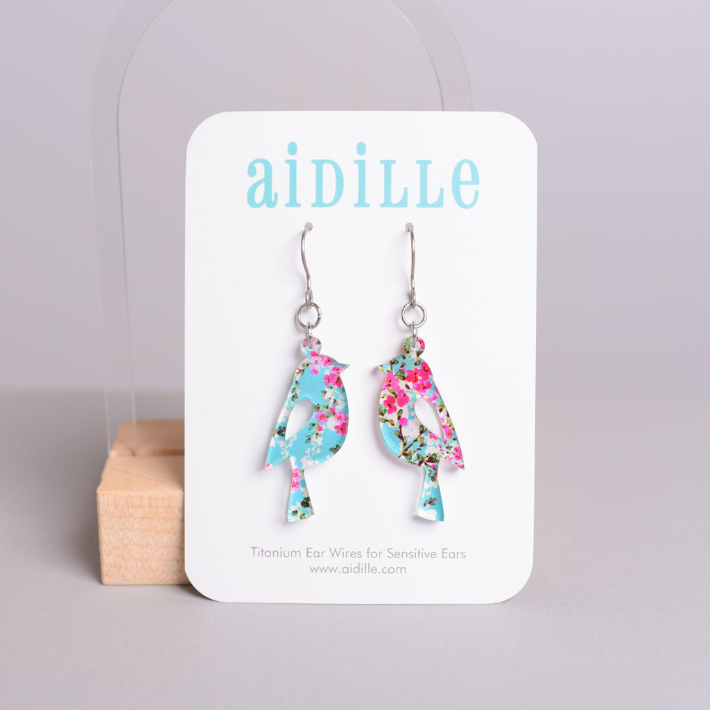 Floral bird earrings on a 'aidille' branded card with a gray background