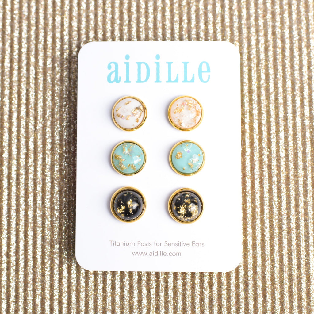 Set of earrings on a 'aidille' branded card against a textured beige background