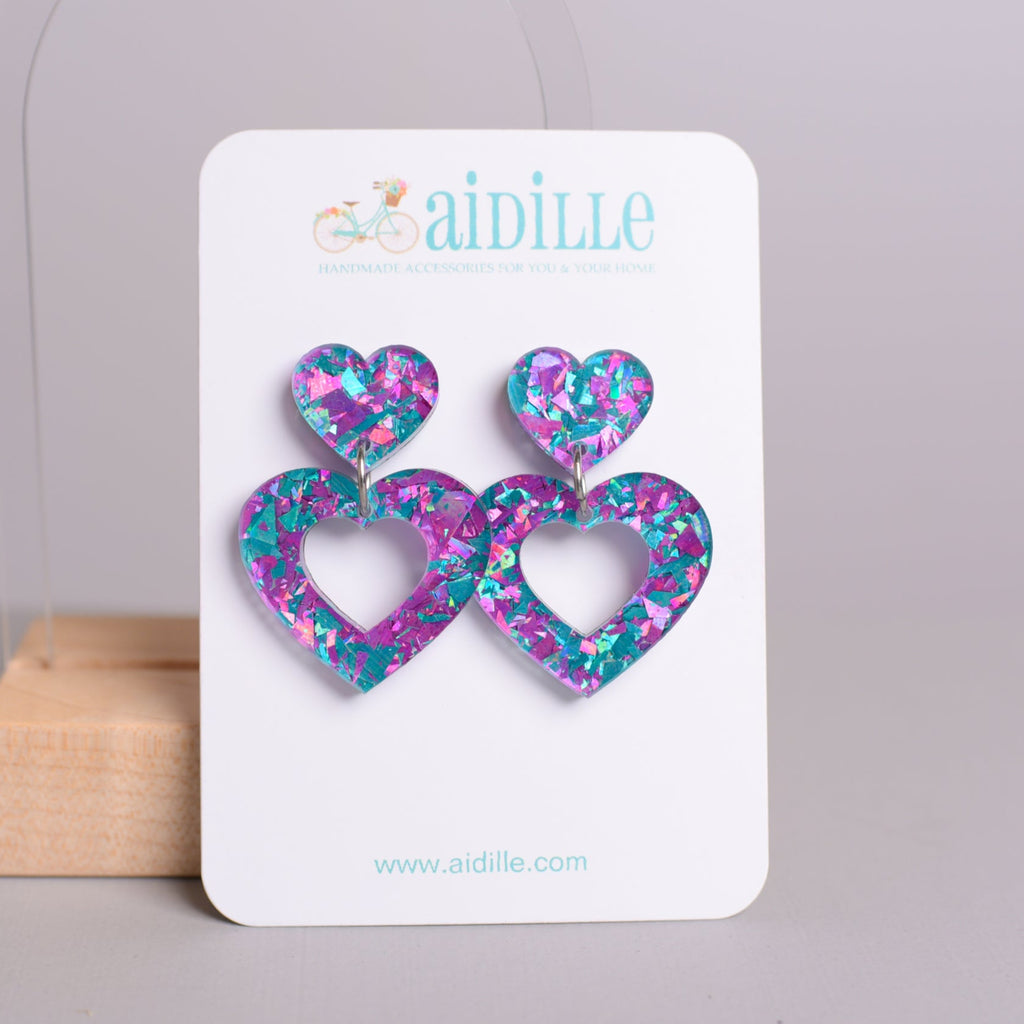 Heart-shaped earrings on a card with 'aidille' branding against a gray background