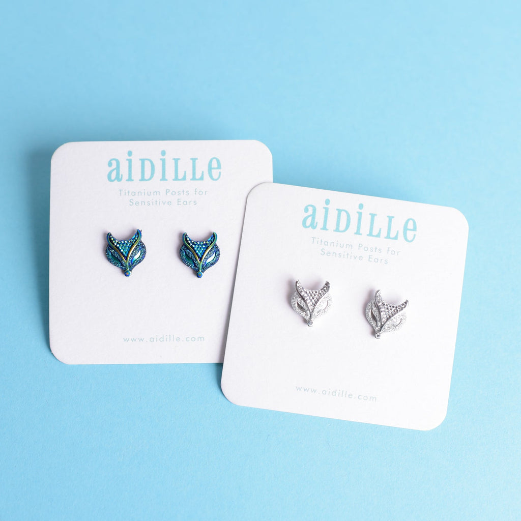 Pair of fox-shaped earrings on 'aidille' branded cards against a light blue background