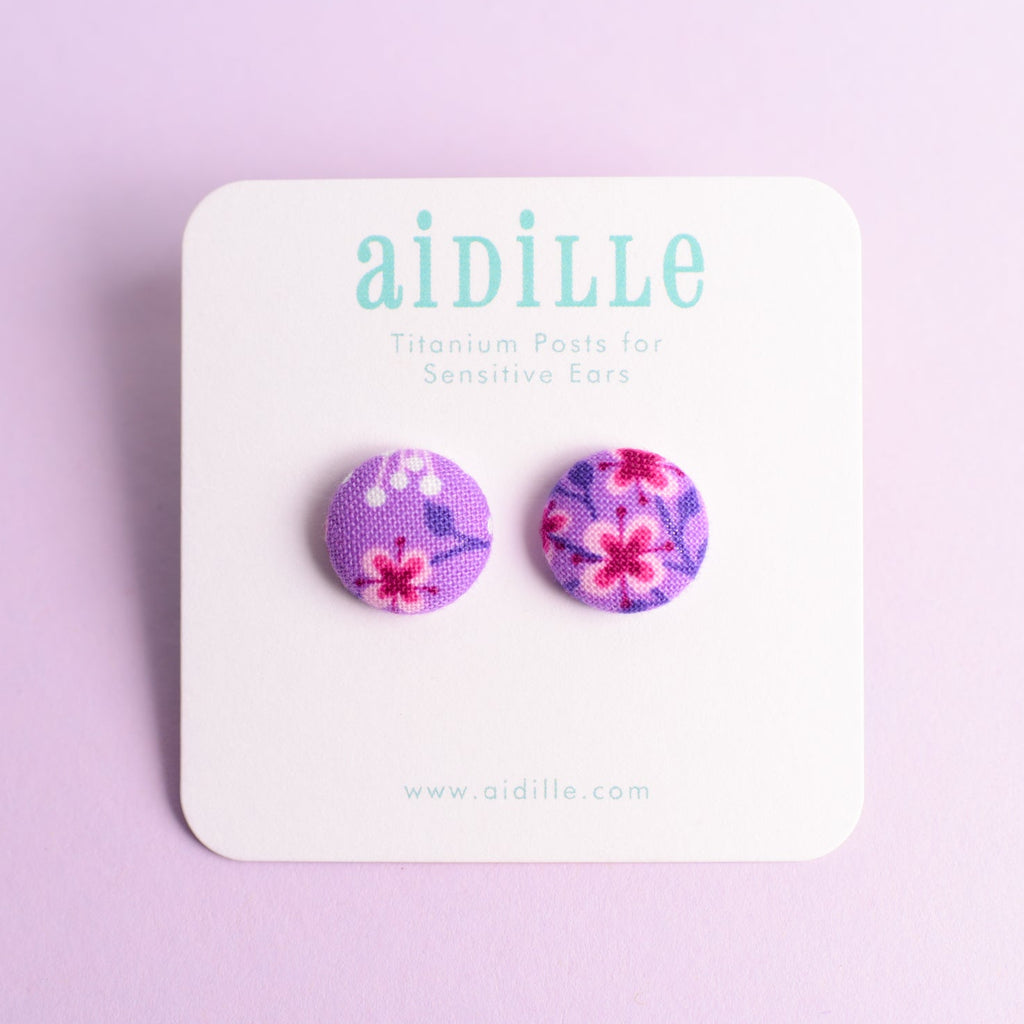Pair of floral earrings on a 'Aidille' branded card against a light purple background