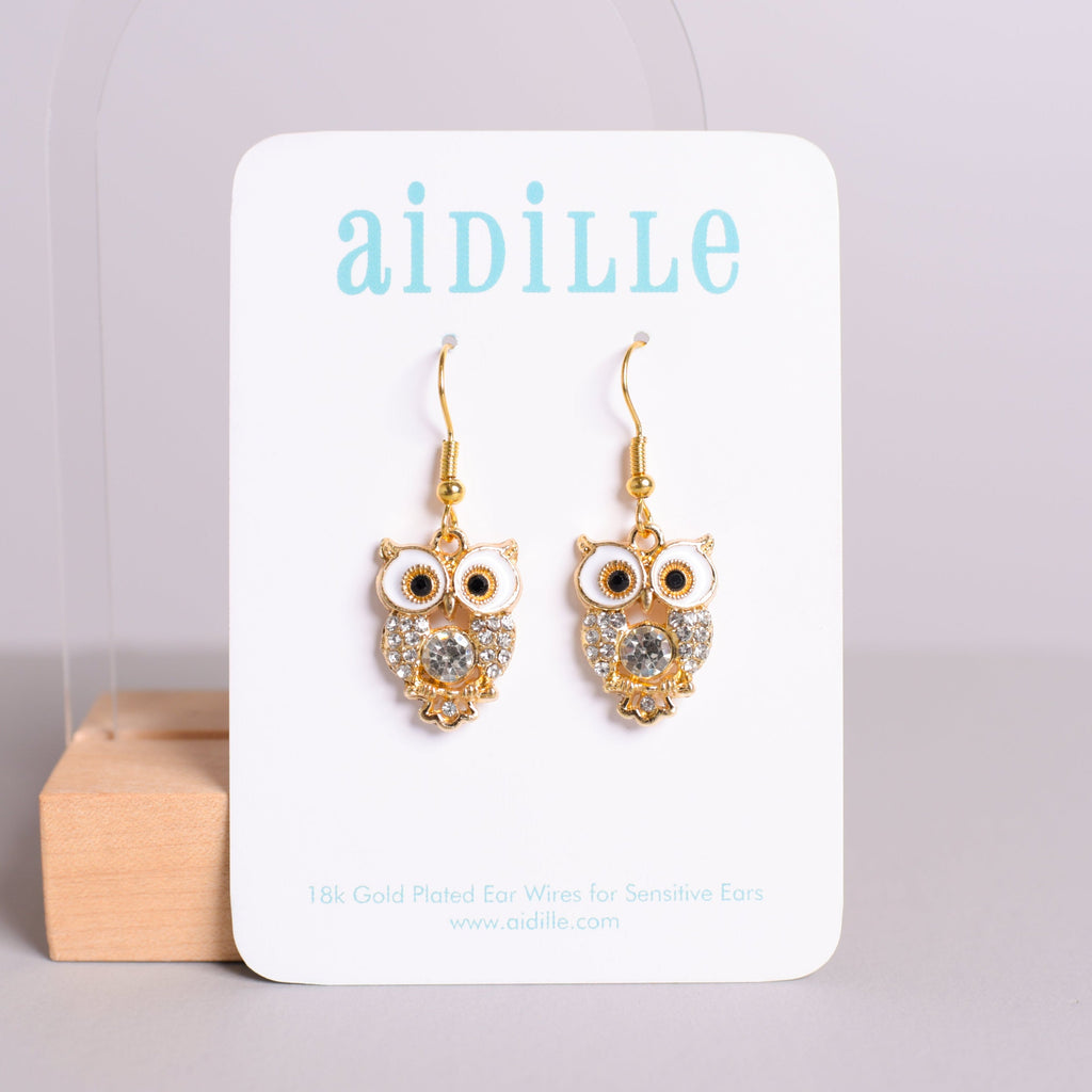 Gold owl-shaped earrings on a 'aidille' branded card against a light gray background