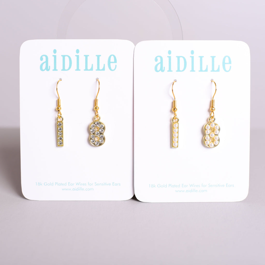 Pair of gold earrings on 'aidille' branded card against a light gray background